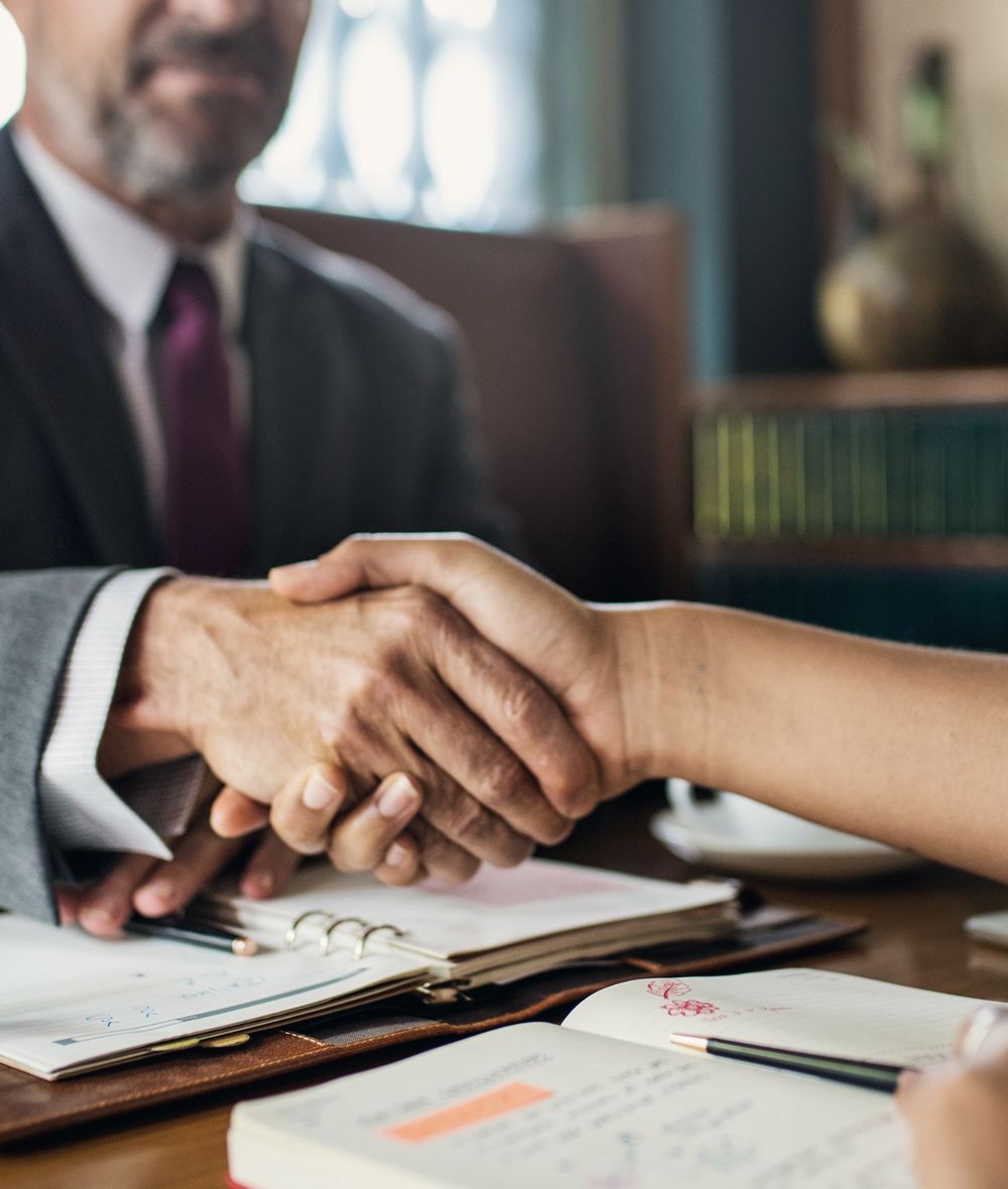An attorney shaking hands with a client across a desk